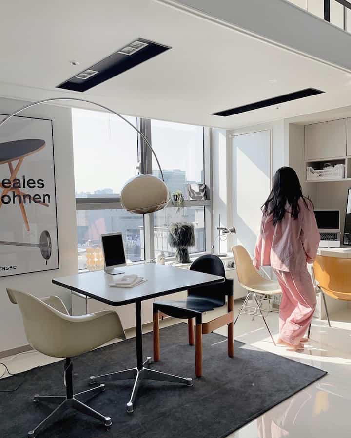 明るいホワイトトーンのホームオフィス、中央に黒いテーブルと様々な椅子が配置されたモダンな雰囲気のあるインテリア。