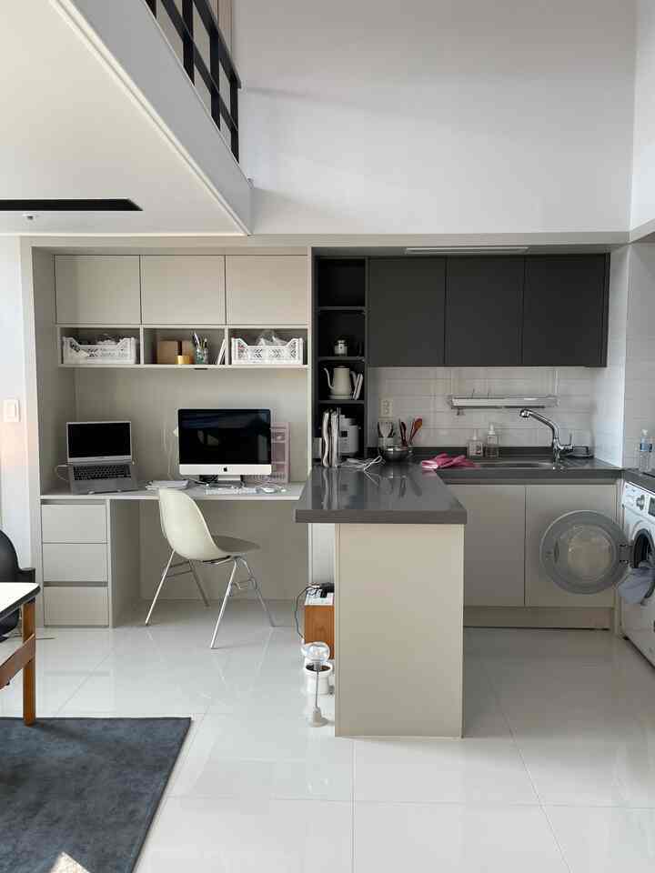 白とグレーのトーンで統一されたワンルームのキッチンとホームオフィス、清潔感のあるモダンなインテリア