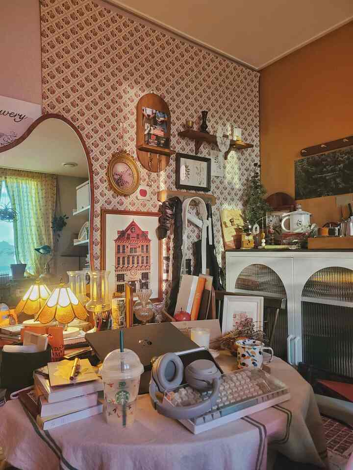 ブラウンとベージュの色調の部屋、ヴィンテージの額縁と照明が配置されたホームオフィス兼ワークスペース