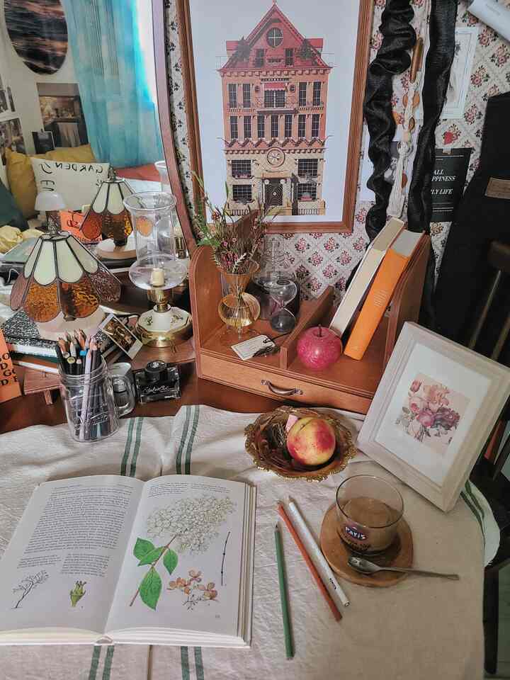 Vintage-inspired study space featuring wooden dining table, vases, picture frames, and a prominent poster with a warm cozy atmosphere