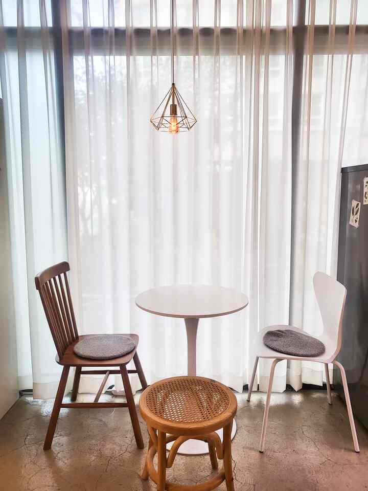 Bright modern small cafe-style space featuring white round table and wood tone chairs