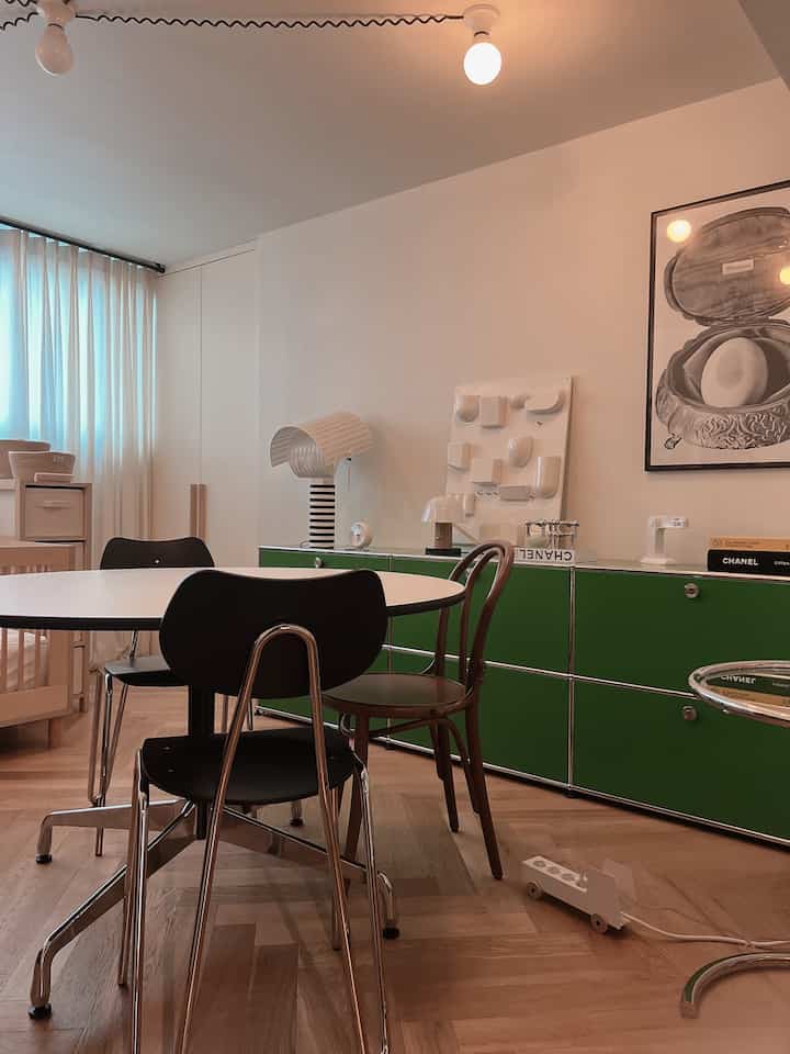 Natural-toned kids' room featuring a green and black coordinated round table and baby crib