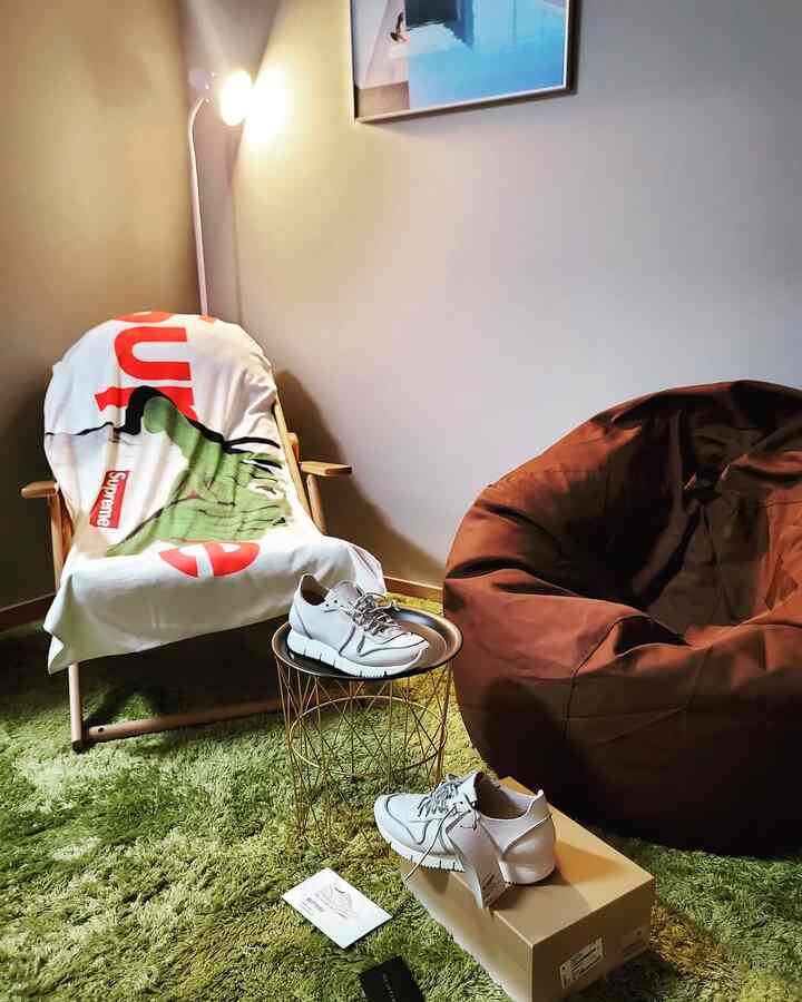 Cozy small living room in calm green and brown tones featuring a grass rug, bean bag chair, and an armchair
