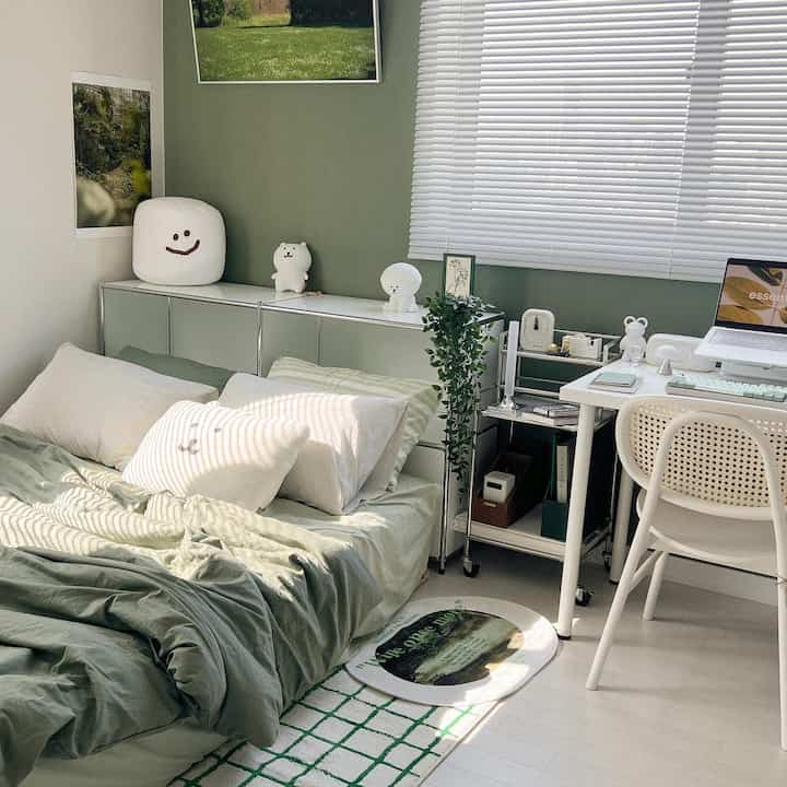 緑色調の寝室に収納キャビネットとナイトテーブル、デスクが配置された自然な雰囲気のインテリア