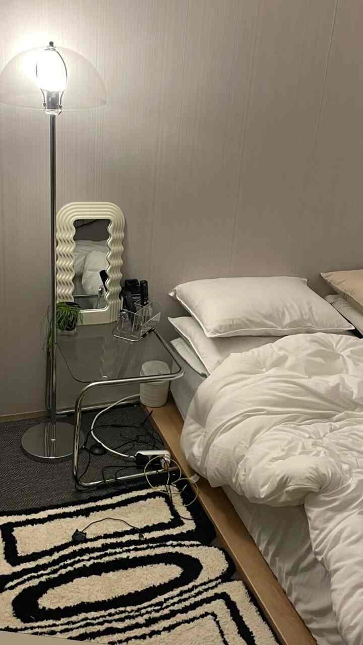 白とナチュラルカラーのトーンのモダンで居心地の良い寝室、ベッドとナイトテーブル、フロアランプが配置された空間