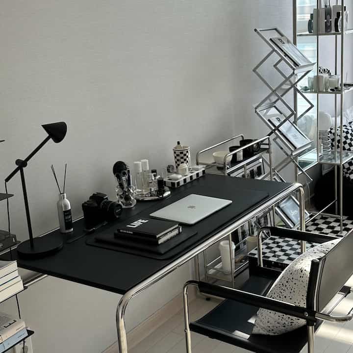 Monotone, neutral-toned mid-century modern home office featuring a black desk and chair as focal points in a neat workspace