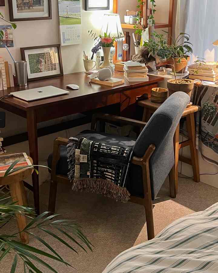 Warm wood tones and beige floor in a home office space featuring a desk, chair, and plants creating a cozy work environment