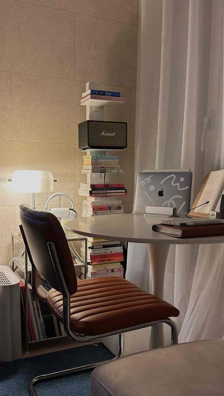 Bright white and brown toned study space featuring a round table and leather cantilever chair, cozy reading corner