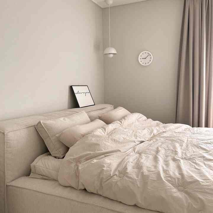 Beige and ivory toned bedroom featuring a large bed and blackout curtains, creating a simple and natural atmosphere