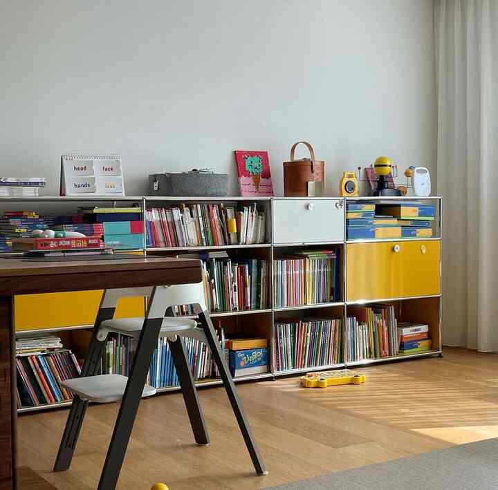 White and yellow toned living room featuring a dining table and children's bookshelf creating a cozy atmosphere
