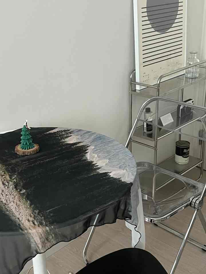 Modern dining room featuring a round table with a nature-print tablecloth and transparent chairs, creating a clean and stylish atmosphere