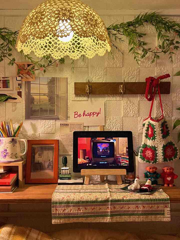 温かみのある木目調とヴィンテージスタイルの小さなデスクスペース、ガーランドとコートハンガーが配置された居心地の良いホームオフィス