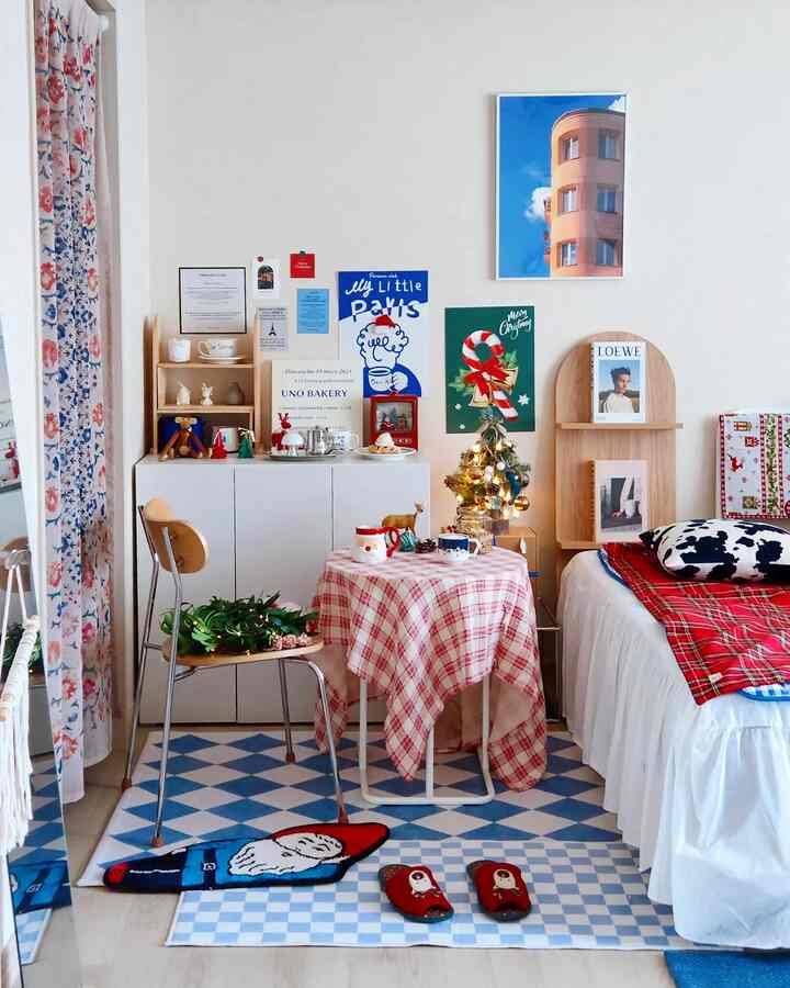 Bright-toned studio bedroom featuring checkered rugs, small round table, and decorative posters creating cozy atmosphere