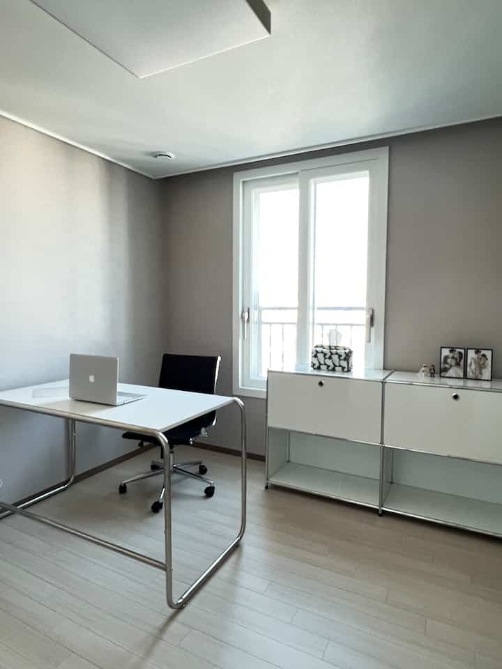 ホワイトとグレーのトーンの小さなホームオフィス、シンプルなデスクと収納キャビネットが配置された落ち着いた空間