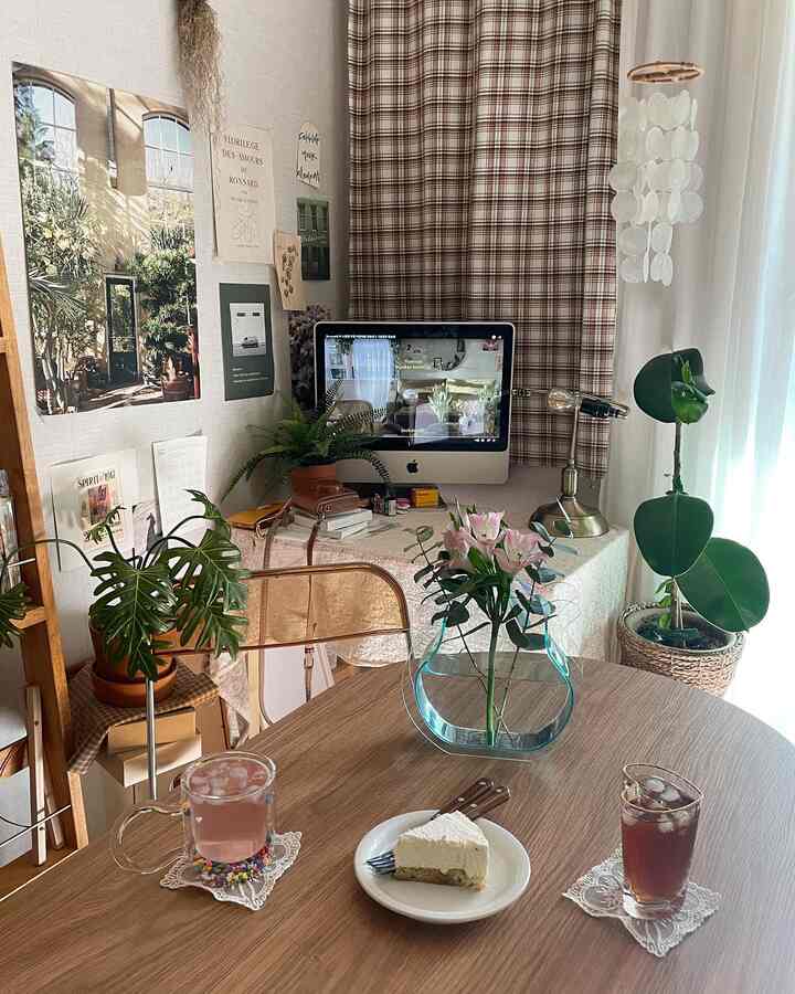 Cozy living room with warm wood tones and vintage style home office setup, featuring plants and a table set with cake and drinks