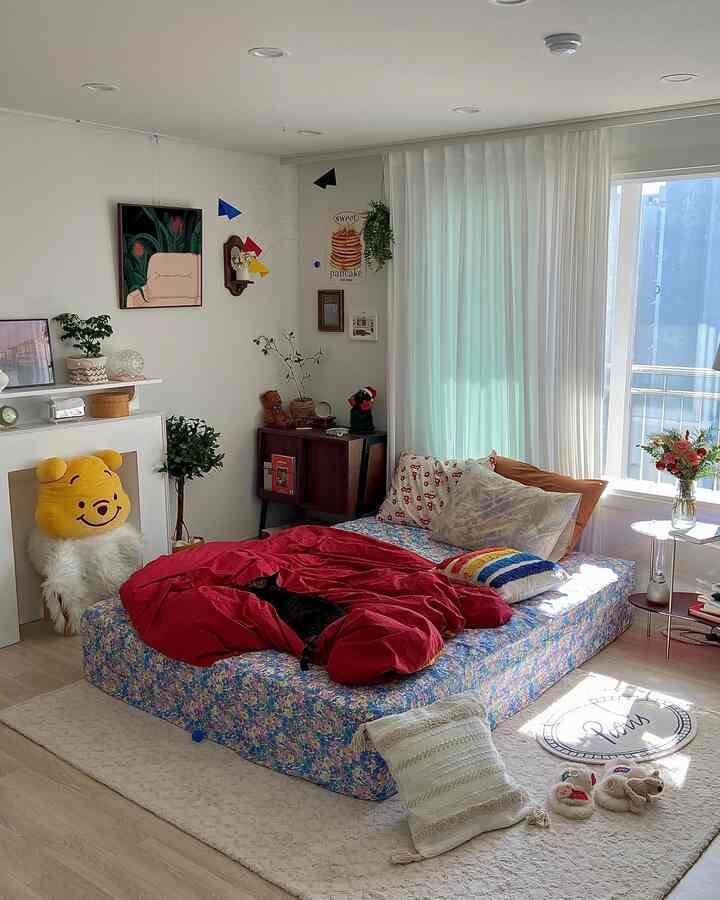 A cozy bedroom with white and red tones featuring a bed adorned with rainbow and Coir Line cushions under soft natural light