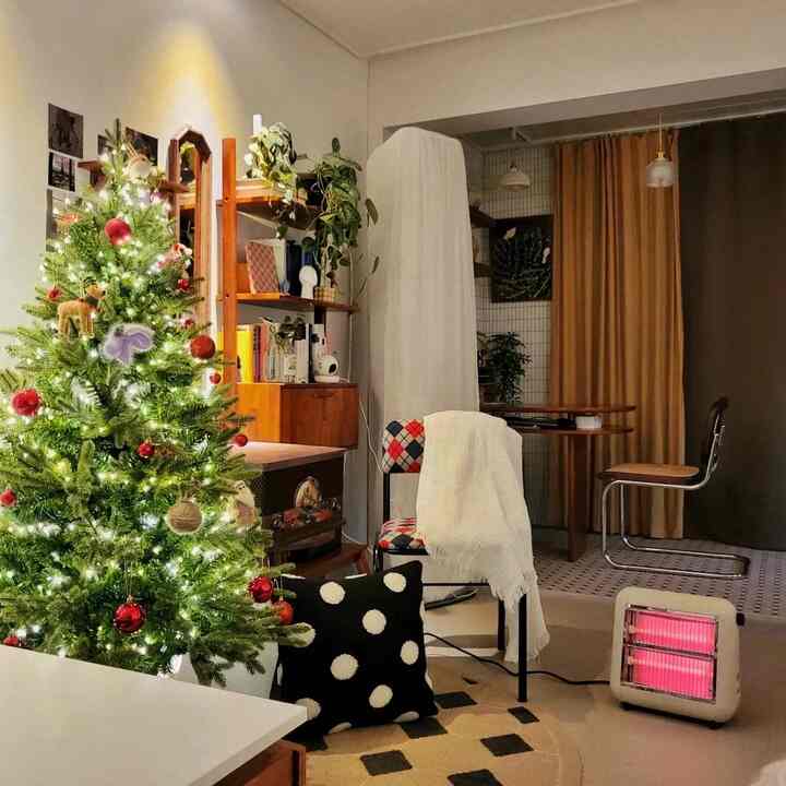 Natural-toned living room featuring a decorated Christmas tree, wood furniture, and brown blackout curtain creating a warm atmosphere