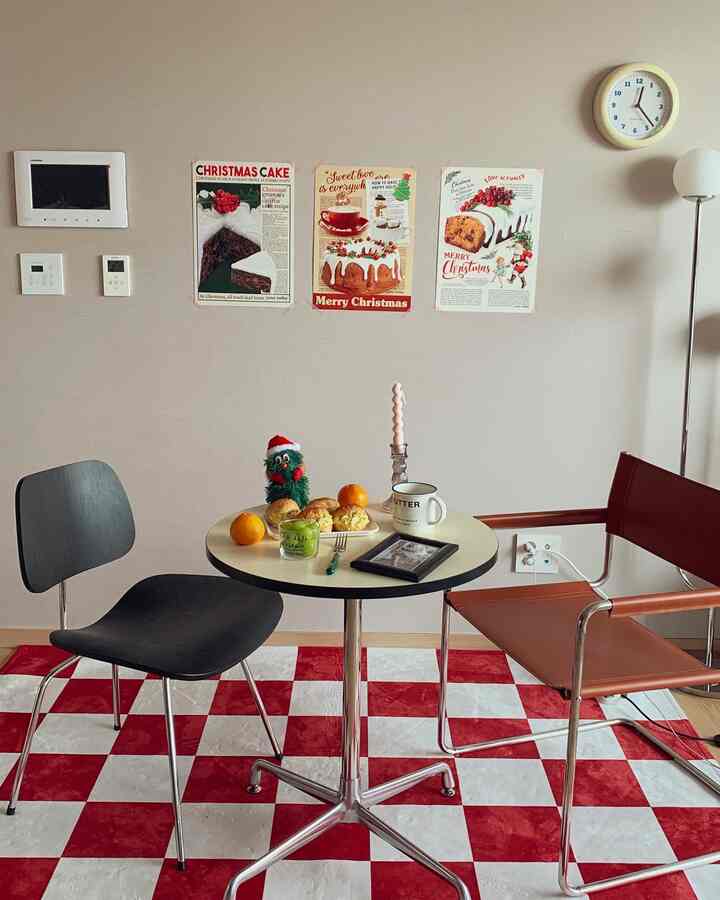 Red and white round table and chairs in living room with Christmas posters and candle decoration, creating a warm festive atmosphere