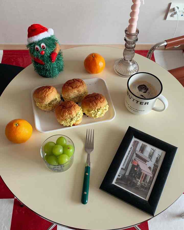 Mid-Century Modern styled pale yellow round table featuring home cafe elements with egg sandwiches, coffee, fruits, and a picture frame