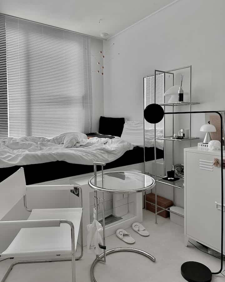 モノトーンの小さなワンルーム寝室、ブラインドと収納ベッドが配置されたシンプルでモダンなインテリア