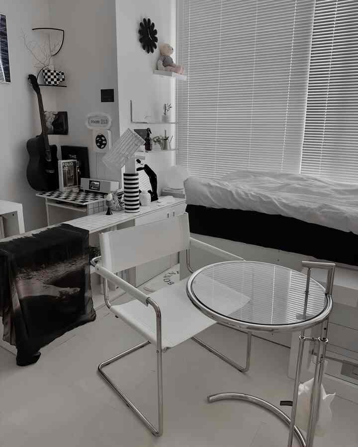 Bright bedroom in white and metal tones featuring a clean armchair and glass side table with a modern atmosphere