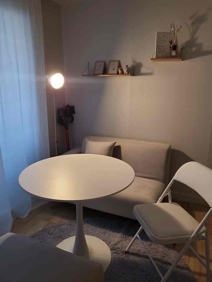 ベージュとホワイトの色調のリビング、コンパクトなソファと丸いコーヒーテーブルが配置された落ち着いた空間