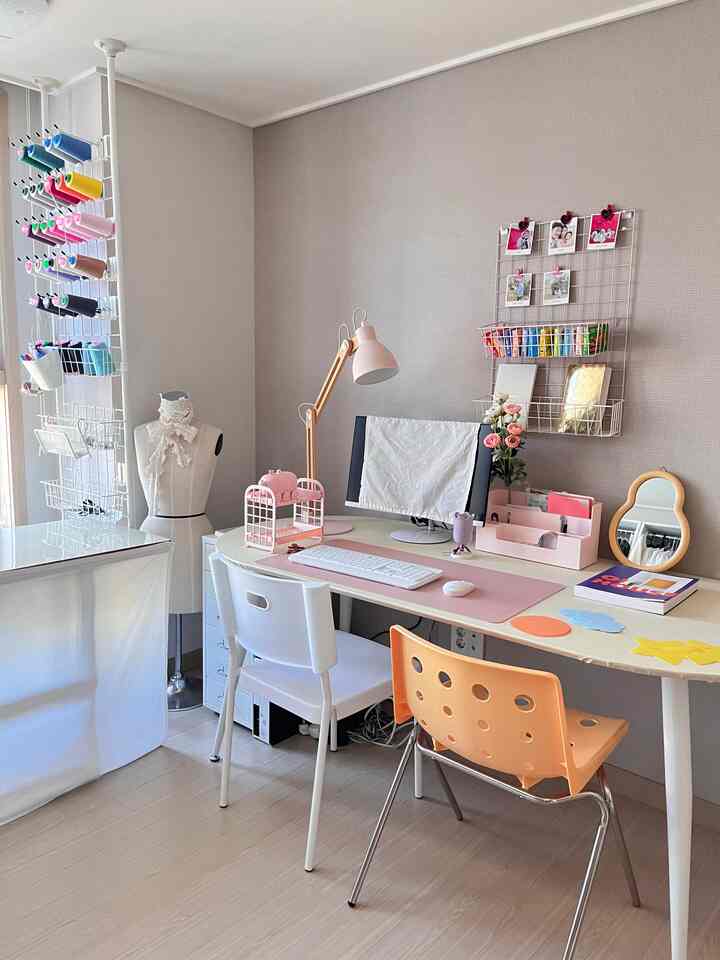 White and pink toned walk-in closet combined home office featuring tidy desk and chairs