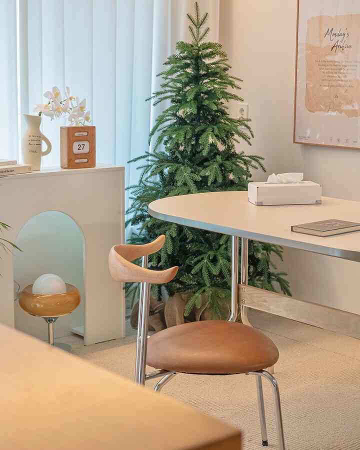 ナチュラルカラーのリビング、ダイニングテーブルと椅子、植物、花瓶、壁掛けアートが配置されたシンプルで落ち着いたインテリア