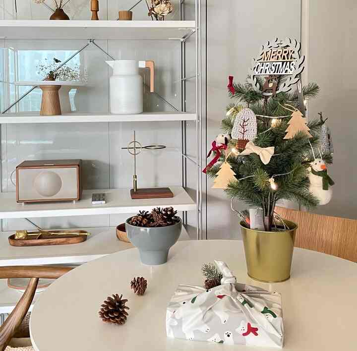 白と木目調のキッチンスペース、棚と小さなクリスマスツリーが配置された雰囲気のあるインテリア