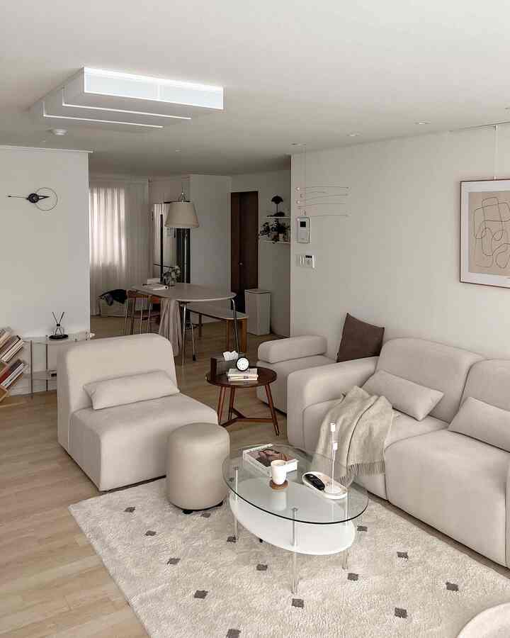 Natural-colored living room featuring beige modular sofa and glass coffee table with a simple and warm atmosphere