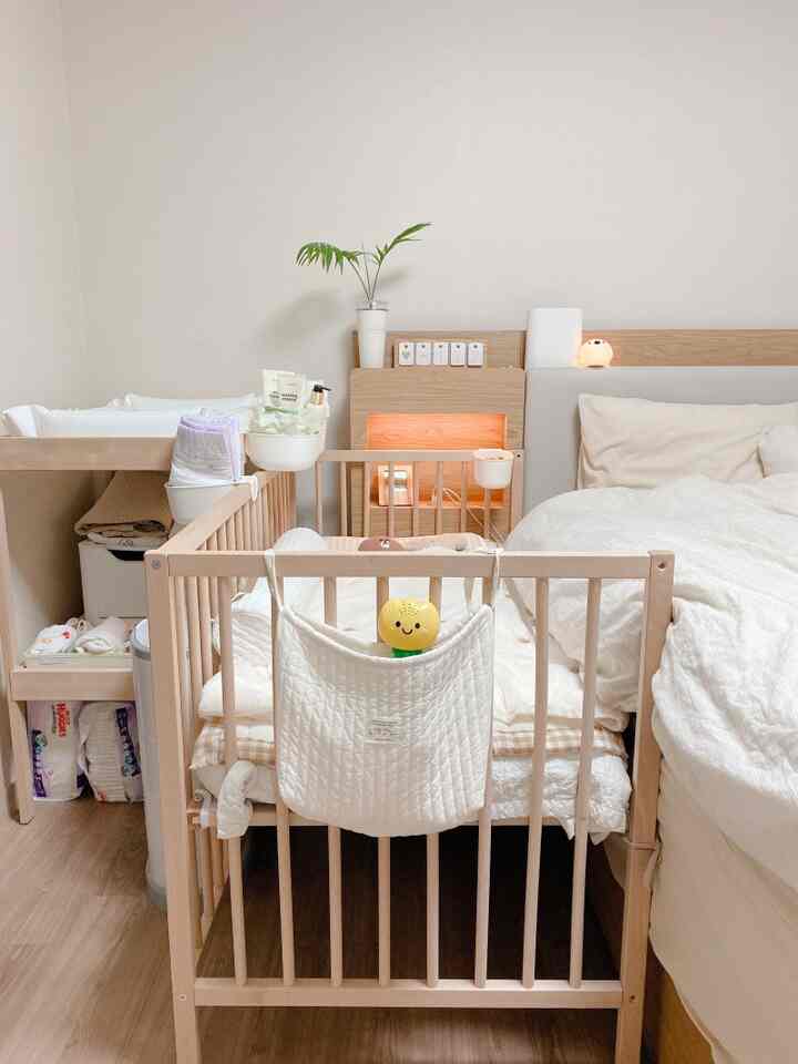 Natural tone bedroom featuring wooden baby crib and changing table with a clean, cozy family atmosphere