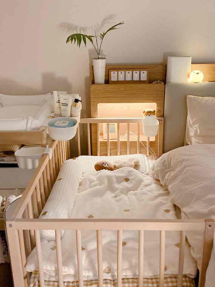 Wood tone and white bedroom featuring baby crib and changing table with cozy atmosphere