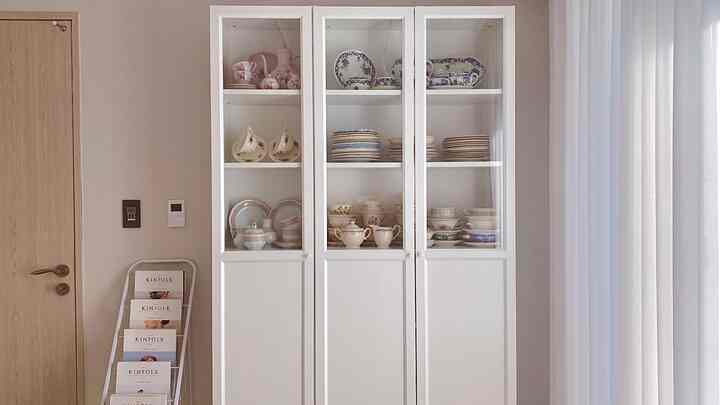 Soft ivory and white toned kitchen space featuring a china cabinet filled with vintage Zwiebelmuster tableware, creating a cozy atmosphere