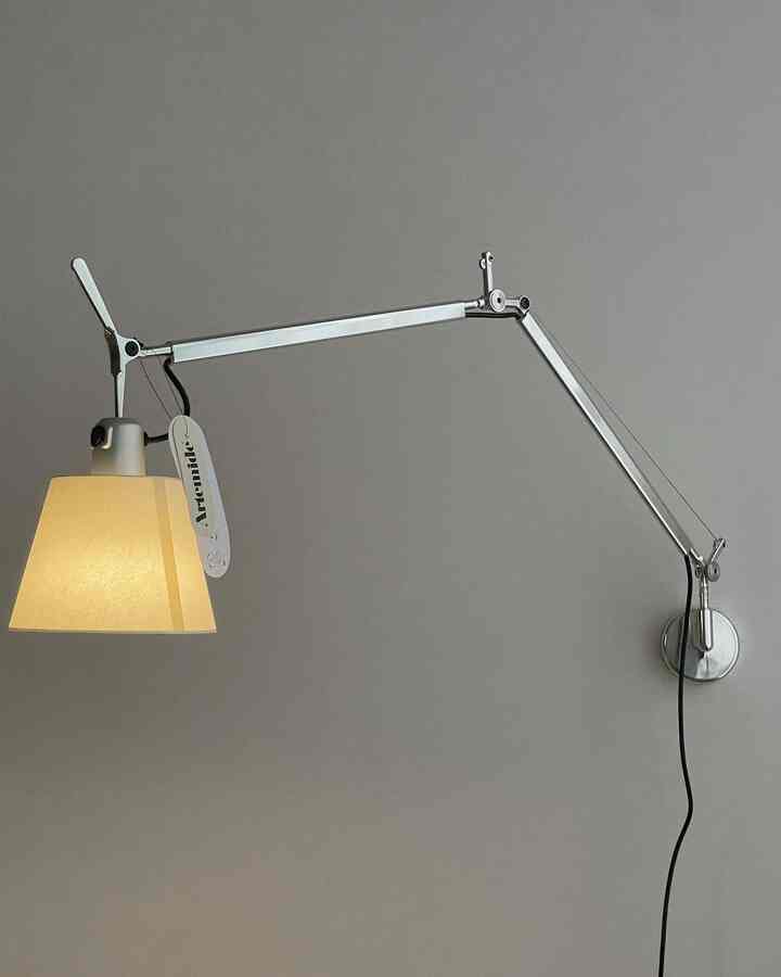 Simple interior space featuring an Artemide silver wall sconce mounted on a gray wall