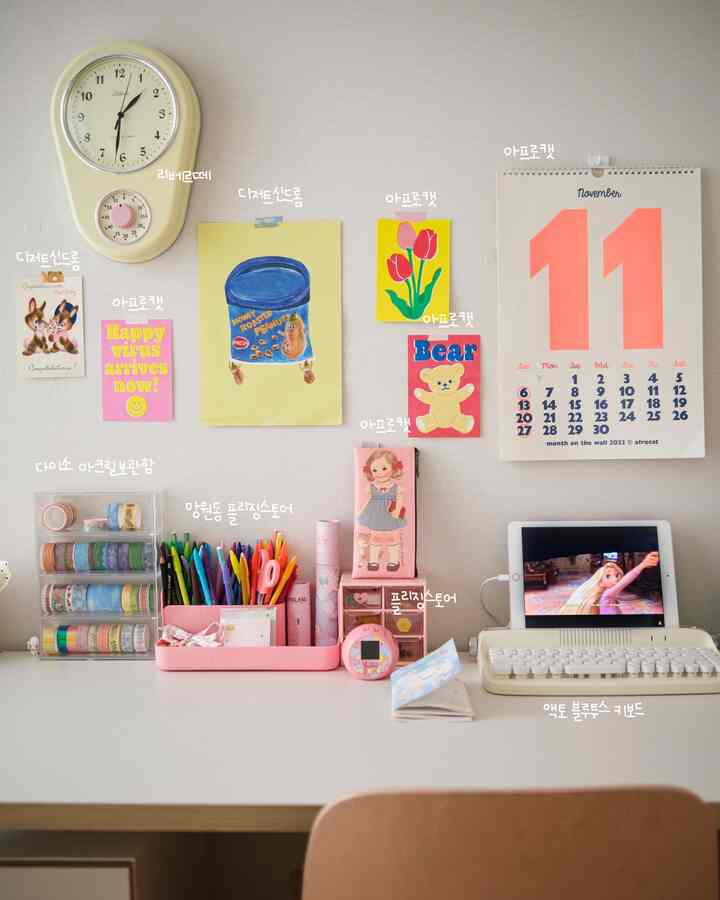 Pink and ivory toned home office space featuring a clock, calendar, and a desk organized with various stationery and accessories