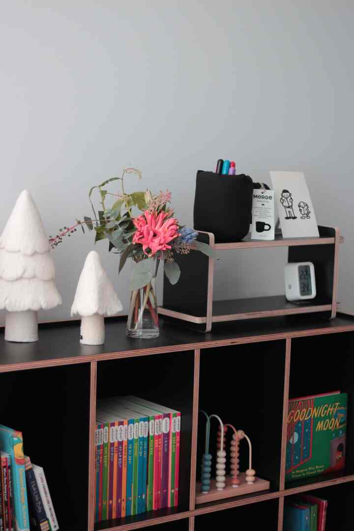 白と黒のトーンの子供部屋、本棚や赤ちゃん用おもちゃ、花瓶が配置された雰囲気のあるインテリア