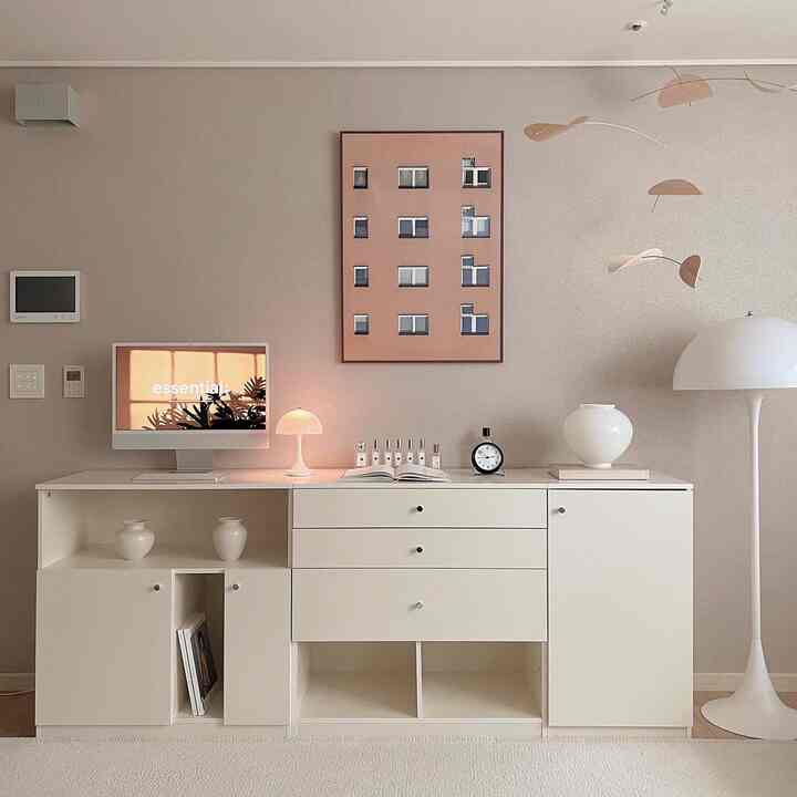 Beige-toned wall with white modular storage cabinet, table and floor lamps in a simple modern living room