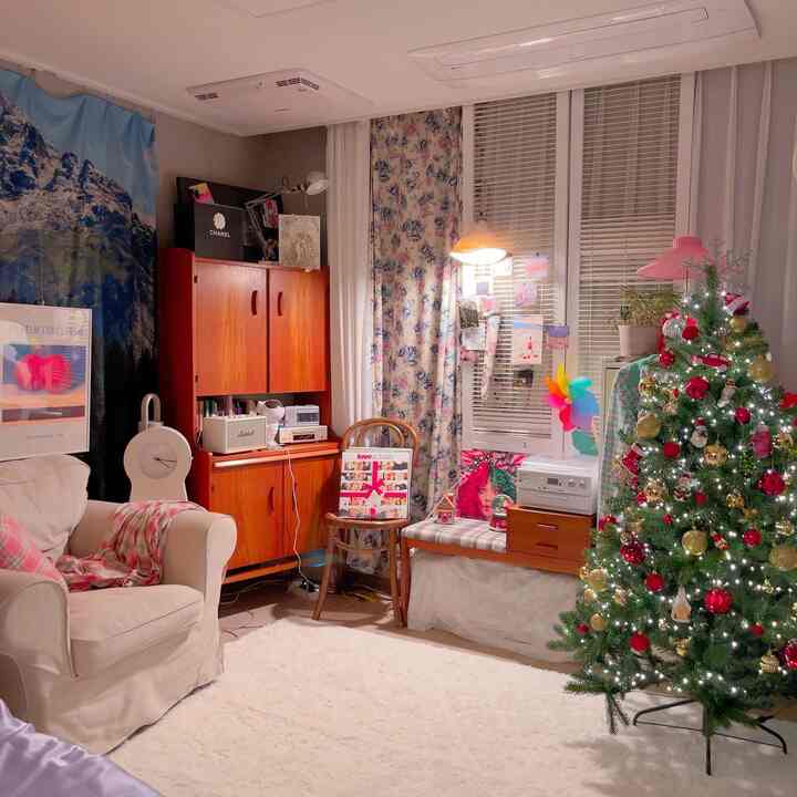 Living room in ivory and wood tones featuring a decorated Christmas tree, fluffy rug, and thick floral curtains with a cozy atmosphere