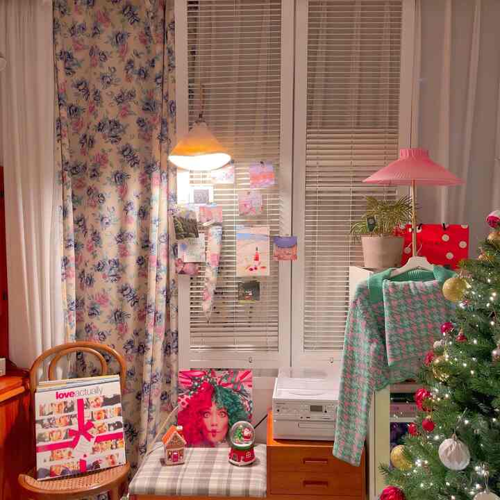 花柄のカーテンと白いブラインドがある小さなダイニングルーム、クリスマスツリーと温かい照明が織りなす雰囲気のあるインテリア