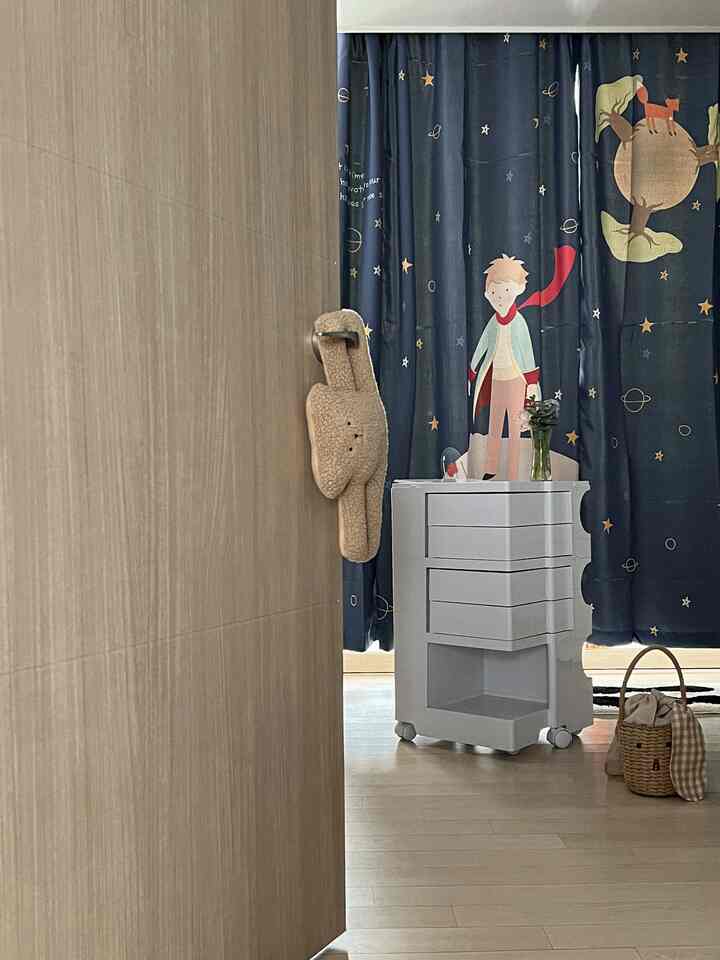 Beige wood floor and door room featuring The Little Prince blackout curtains and white storage trolley with vase, a kids' space