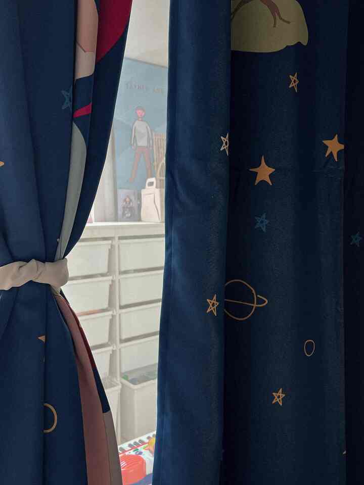 子供部屋の青い色調の遮光カーテンと背景に子供向けの収納や装飾が配置された雰囲気のあるインテリア