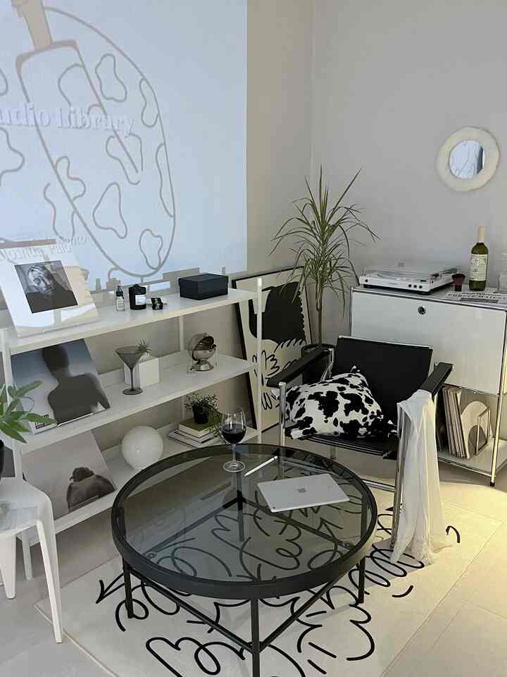 White and black toned living room featuring a round glass coffee table and minimalist shelving, cozy simple modern style space