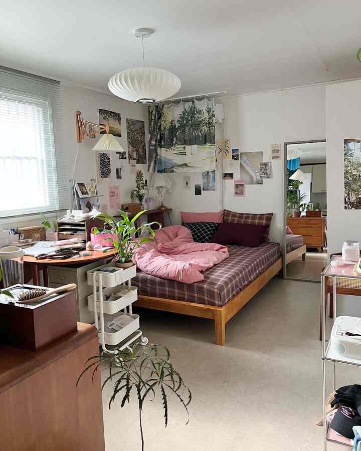 Bright-toned bedroom featuring a wooden bed with pink bedding and various plants creating a cozy atmosphere