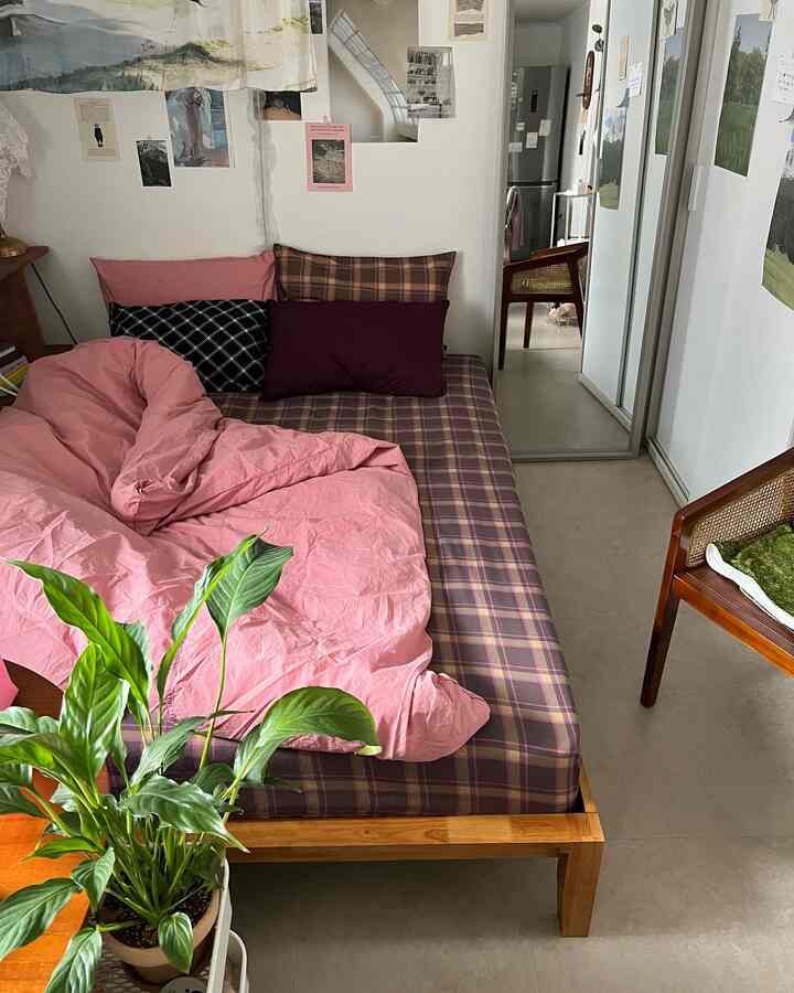 Natural-toned bedroom featuring a wooden bed with pink bedding and pillows