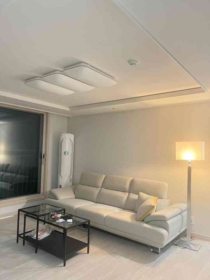 白とグレーのトーンのリビング、モダンなソファとフロアランプが配置された印象的で落ち着いた空間