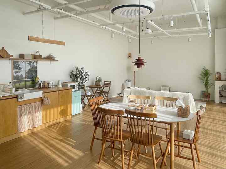 White and wood tone living and dining area featuring a wooden dining table with chairs, pendant light, and sofa creating a warm atmosphere