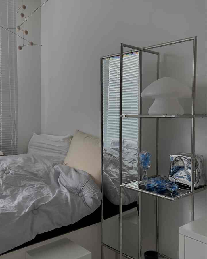 White-toned bedroom featuring neat bedding and modular full-length mirror shelf with a modern and simple atmosphere