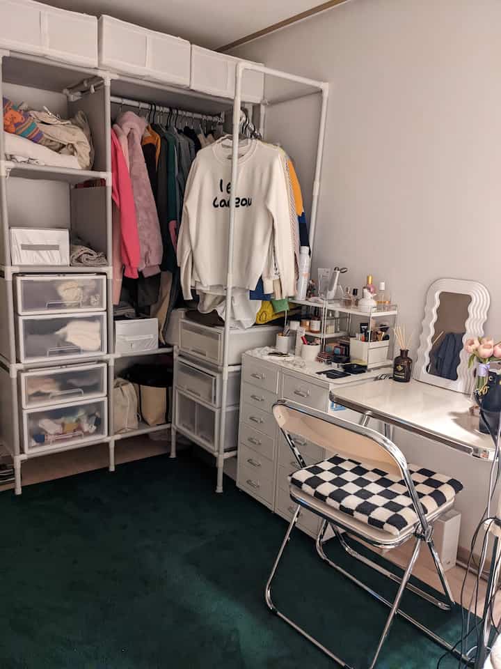 白とダークグリーンのトーンのワンルーム、折りたたみテーブルと無ボルトドレスルームハンガーが配置された雰囲気のあるミッドセンチュリーモダンの室内