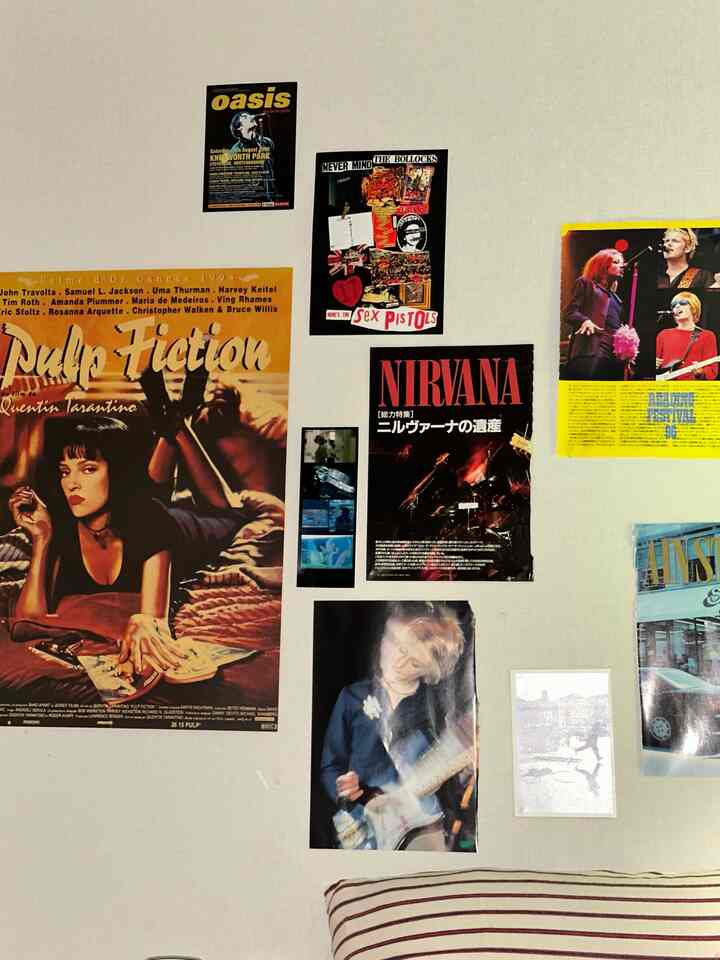 Beige-toned wall adorned with various vintage music and movie posters in a living room setting