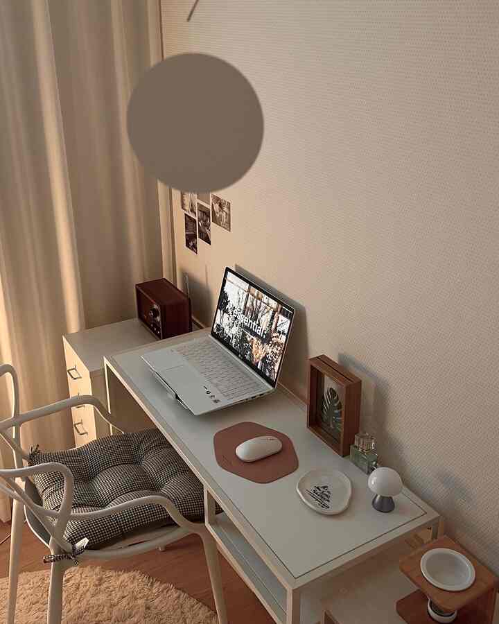 White and brown toned home office space featuring a white desk and chair with a laptop and mouse pad, in a clean minimal interior